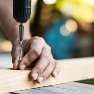 Screw being screwed into a piece of wood by cordless drill. Concept tools and repair work.